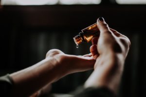 Hand tropft Öl aus einem Fläschchen in andere Hand